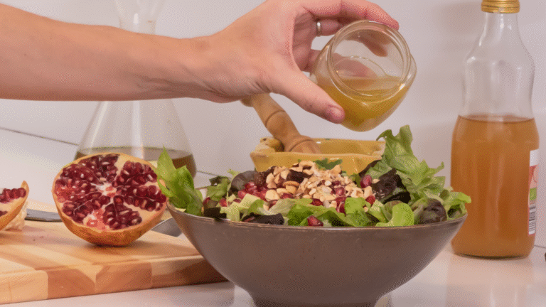 Une main qui sert la vinaigrette artisanale l'aigre douce d'Augusto sur une belle salade.